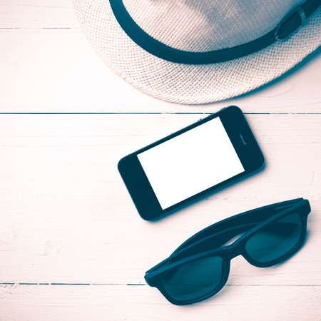 hat sunglasses and smart phone on white table vintage style