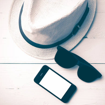 hat sunglasses and smart phone on white table vintage styleの写真素材