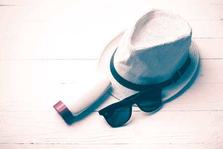 hat sunglasses and body lotion over white table vintage styleの写真素材