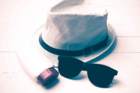 hat sunglasses and body lotion over white table vintage style