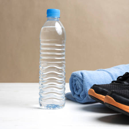 fitness equipment:blue towel,drinking water and running shoes on white wood tableの写真素材