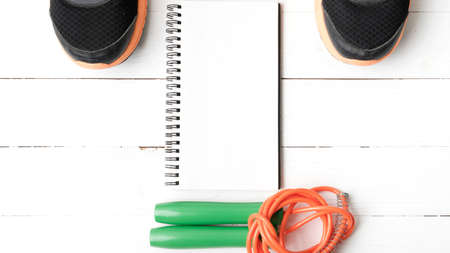 fitness equipment : running shoes,jumping rope and notepad on white wood tableの写真素材