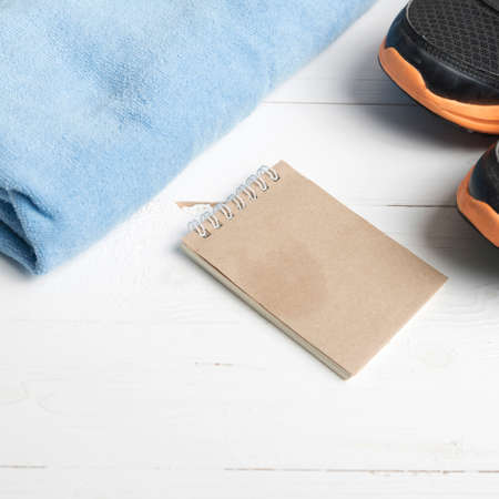 fitness equipment : running shoes,blue towel and notepad on white wood tableの写真素材