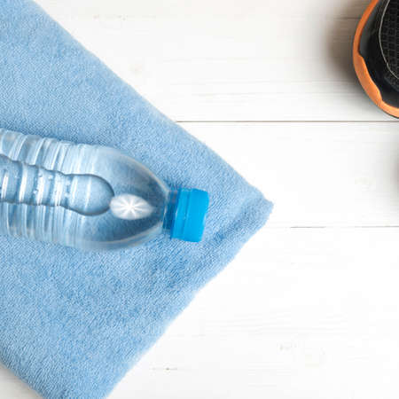 fitness equipment:blue towel,drinking water and running shoes on white wood tableの写真素材