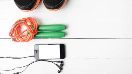 fitness equipment : running shoes,jumping rope and phone on white wood tableの写真素材