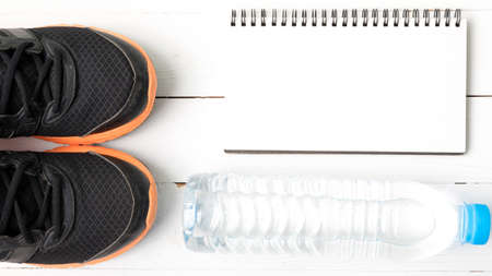 fitness equipment : running shoes,drinking water and notebook on white wood tableの写真素材