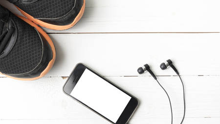 running shoes and phone on white wood tableの写真素材