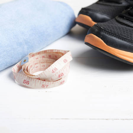 fitness equipment : running shoes,blue towel and measuring tape on white wood tableの写真素材