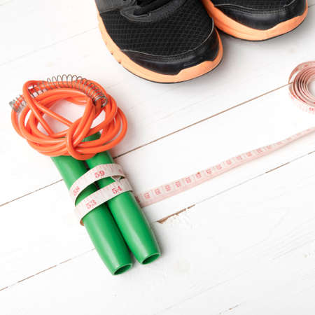 fitness equipment : running shoes,jumping rope and measuring tape on white wood tableの写真素材