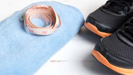 fitness equipment : running shoes,blue towel and measuring tape on white wood tableの写真素材