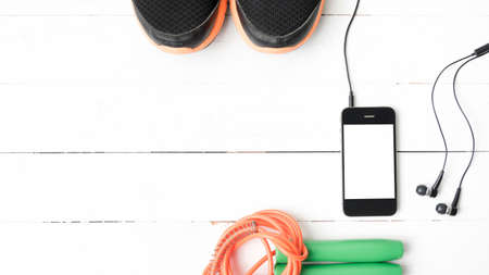 fitness equipment : running shoes,jumping rope and phone on white wood tableの写真素材