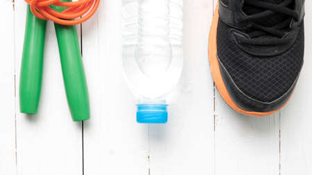 fitness equipment : running shoes,jumping rope and water bottle on white wood tableの写真素材