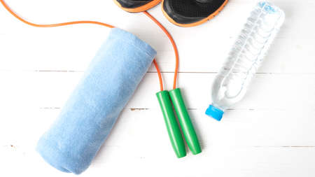 fitness equipment : running shoes,towel,jumping rope and drinking water on white wood tableの写真素材
