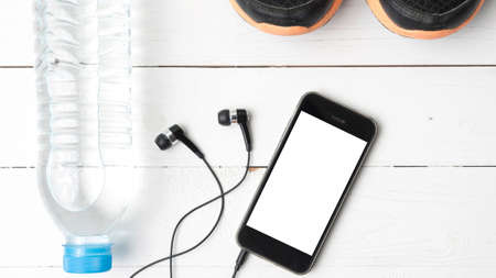 fitness equipment : running shoes,drinking water and phone on white wood tableの写真素材