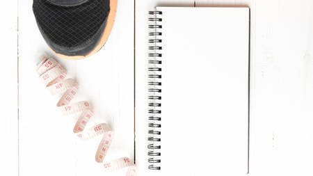 running shoes with notebook and measuring tape on white wood table
