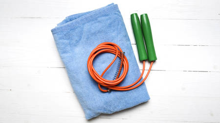 fitness equipment:blue towel,jumping rope on white wood tableの写真素材