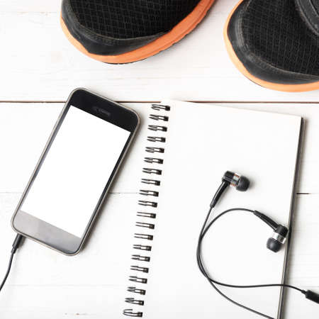 running shoes,notebook and phone on white wood table