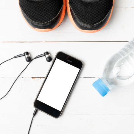 fitness equipment : running shoes,drinking water and phone on white wood tableの写真素材