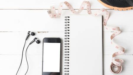 running shoes,measuring tape,notebook and phone on white wood tableの写真素材