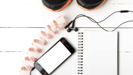 running shoes,measuring tape,notebook and phone on white wood tableの写真素材
