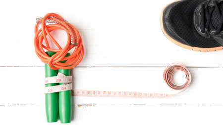 fitness equipment : running shoes,jumping rope and measuring tape on white wood tableの写真素材