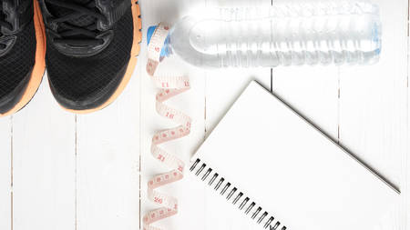 running shoes,measuring tape,drinking water and notebook on white wood tableの写真素材