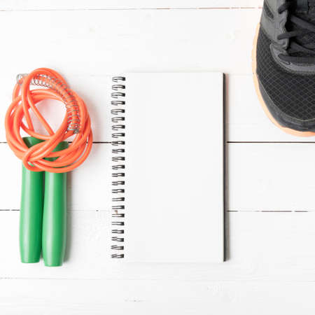 fitness equipment : running shoes,jumping rope and notepad on white wood tableの写真素材