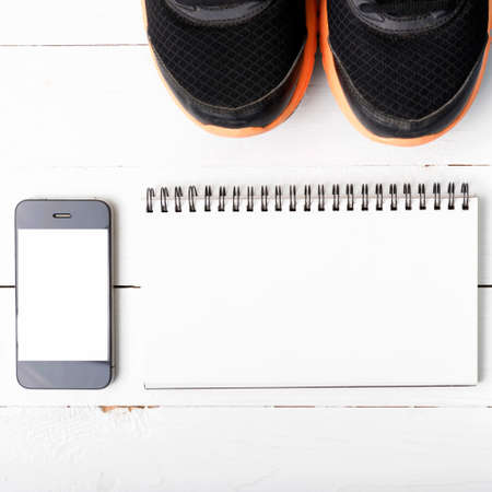 fitness equipment : running shoes,notebook and phone on white wood tableの写真素材