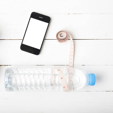 fitness equipment : drinking water,measuring tape and phone on white wood tableの写真素材