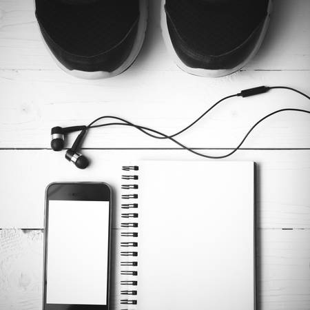 running shoes,notebook and phone on white wood table black and white tone color styleの写真素材