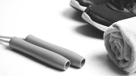 fitness equipment: towel,jumping rope and running shoes on white wood table black and white color styleの写真素材