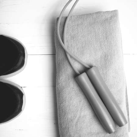 fitness equipment: towel,jumping rope and running shoes on white wood table black and white color styleの写真素材