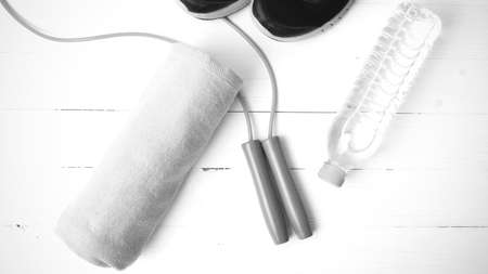 fitness equipment : running shoes,towel,jumping rope and drinking water on white wood table black...