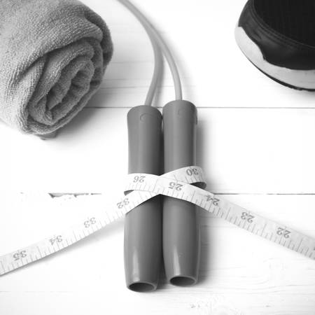 fitness equipment : running shoes,towel,jumping rope and measuring tape on white wood table black...