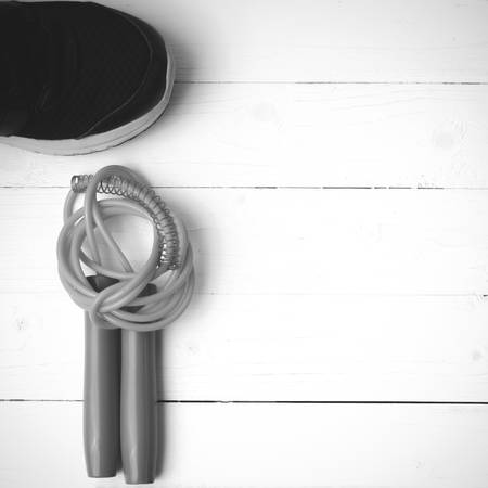 fitness equipment : running shoes,jumping rope on white wood table black and white color tone styleの写真素材