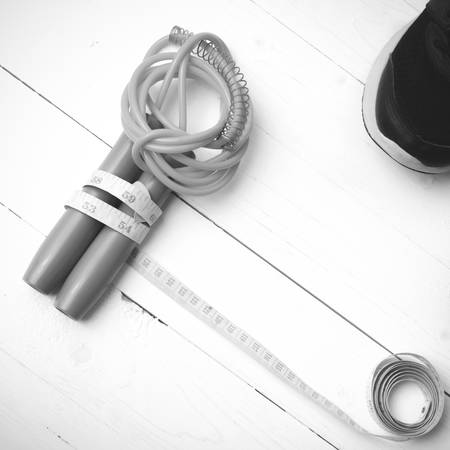 fitness equipment : running shoes,jumping rope and measuring tape on white wood table black and...