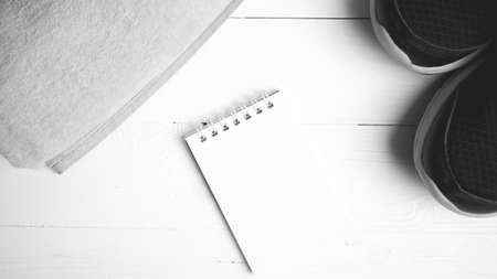 fitness equipment : running shoes,towel and notepad on white wood table black and white color styleの写真素材