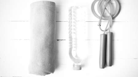 fitness equipment : towel,jumping rope and drinking water on white wood table black and white color tone styleの写真素材
