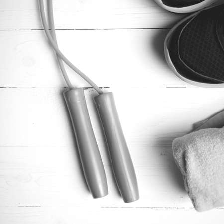fitness equipment: towel,jumping rope and running shoes on white wood table black and white color styleの写真素材