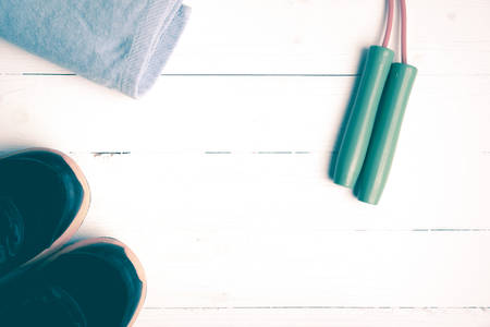 fitness equipment:blue towel,jumping rope and running shoes on white wood table vintage styleの写真素材