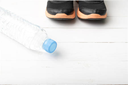 running shoes and drinking water on white table