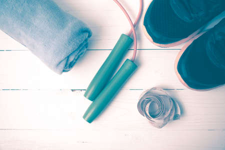 fitness equipment : running shoes,towel,jumping rope and measuring tape on white wood table vintage...