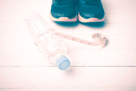 fitness equipment : running shoes,drinking water and measuring tape on white wood table vintage...
