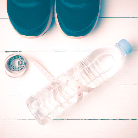 fitness equipment : running shoes,drinking water and measuring tape on white wood table vintage styleの写真素材