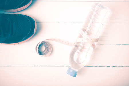 fitness equipment : running shoes,drinking water and measuring tape on white wood table vintage styleの写真素材