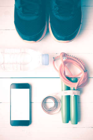 fitness equipment : running shoes,jumping rope,drinking water,measuring tape and phone on white wood...