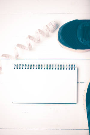 running shoes with notebook and measuring tape on white wood table vintage styleの写真素材