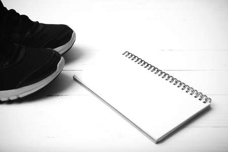 running shoes and notepad on white wood table black and white tone color styleの写真素材