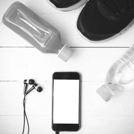 running shoes,orange juice,drinking water and phone on white wood background black and white tone color styleの写真素材