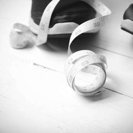 running shoes and measuring tape on white wood table black and white tone color styleの写真素材